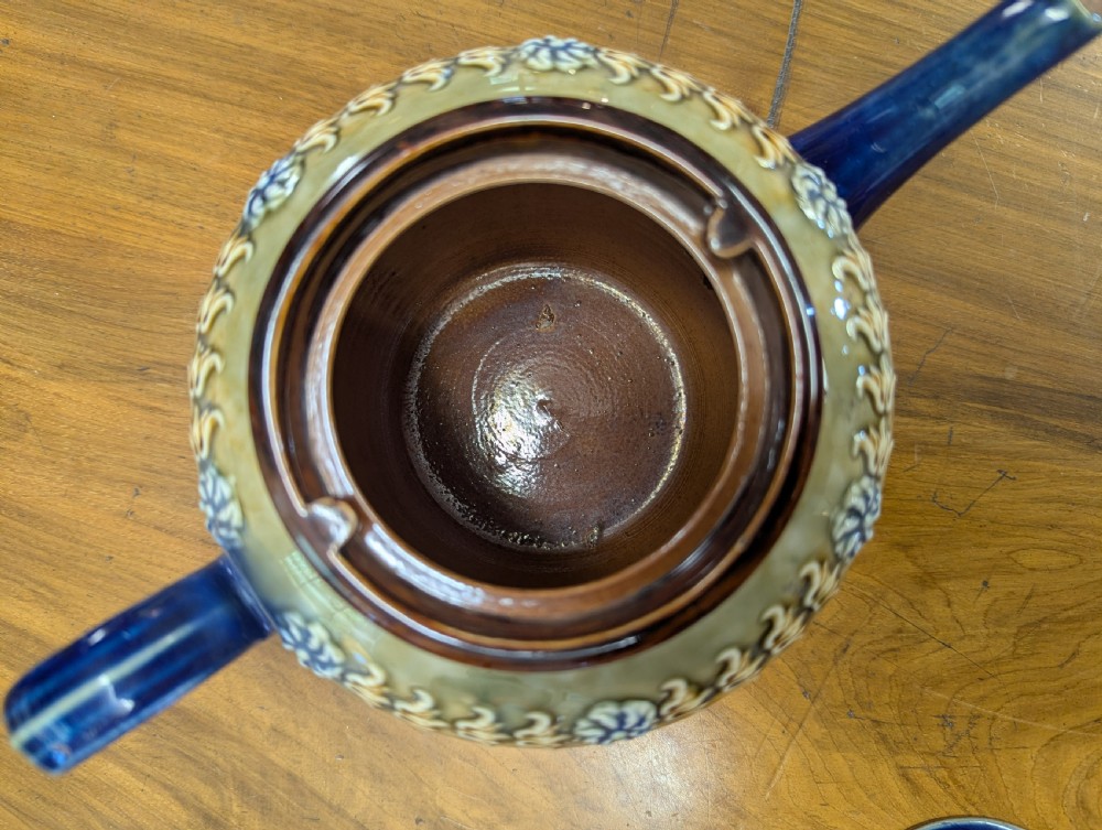 An Art Nouveau Royal Doulton stoneware teapot featuring a cobalt blue base, an olive green shoulder with raised relief patterns, and a fitted lid. View X