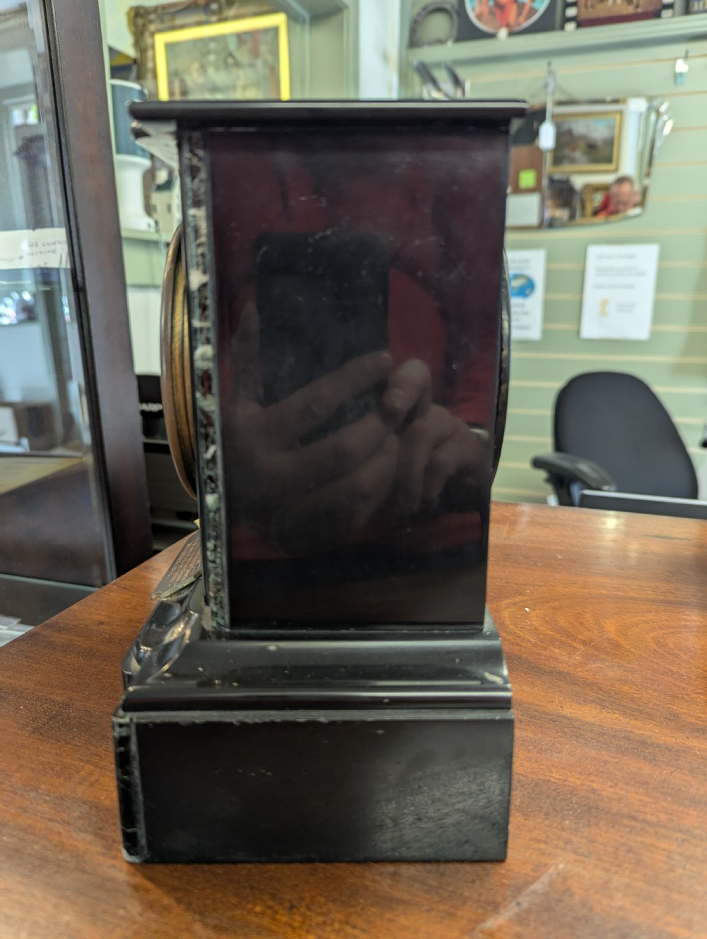 A Victorian black marble and slate mantel clock featuring incised gilded floral patterns, a white enamel dial with Roman numerals, and a brass presentation plaque. View II