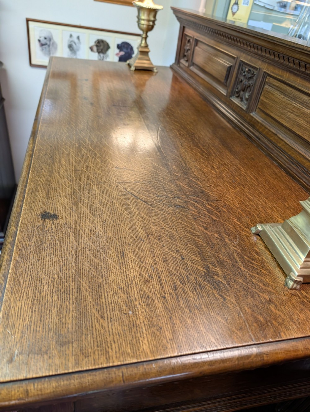 A late Victorian carved oak buffet featuring two top drawers with brass drop handles, an open tier, and a lower double-door cabinet decorated with detailed carved foliage. View VI