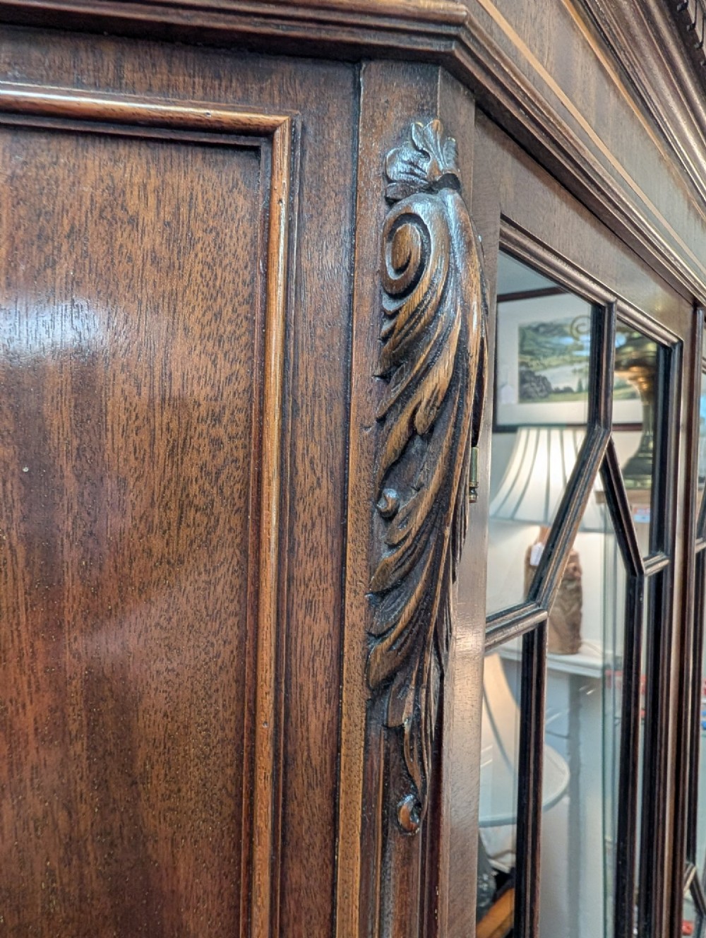 An Edwardian mahogany corner display cabinet featuring a swan-neck pediment, astragal glazed top doors, and lower inlaid timber panelled doors. View IV