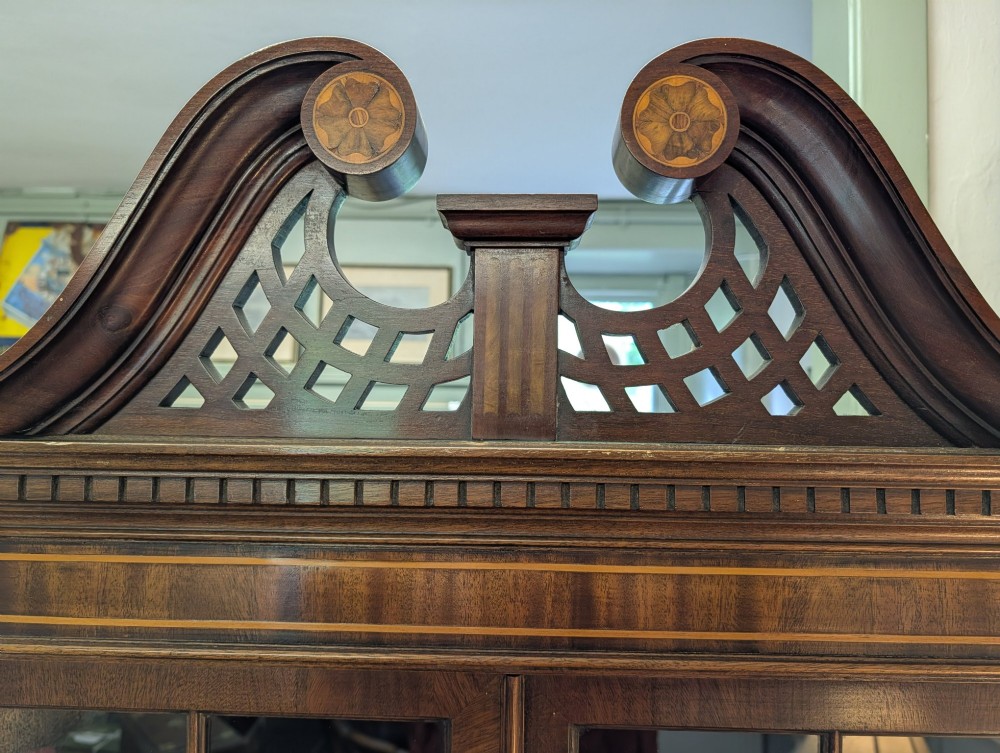 An Edwardian mahogany corner display cabinet featuring a swan-neck pediment, astragal glazed top doors, and lower inlaid timber panelled doors. View V