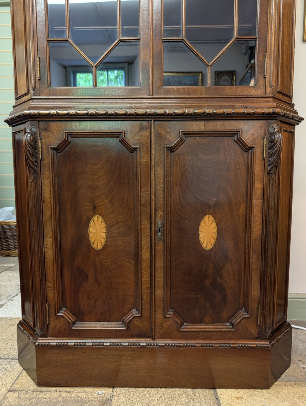 An Edwardian mahogany corner display cabinet featuring a swan-neck pediment, astragal glazed top doors, and lower inlaid timber panelled doors. View IX
