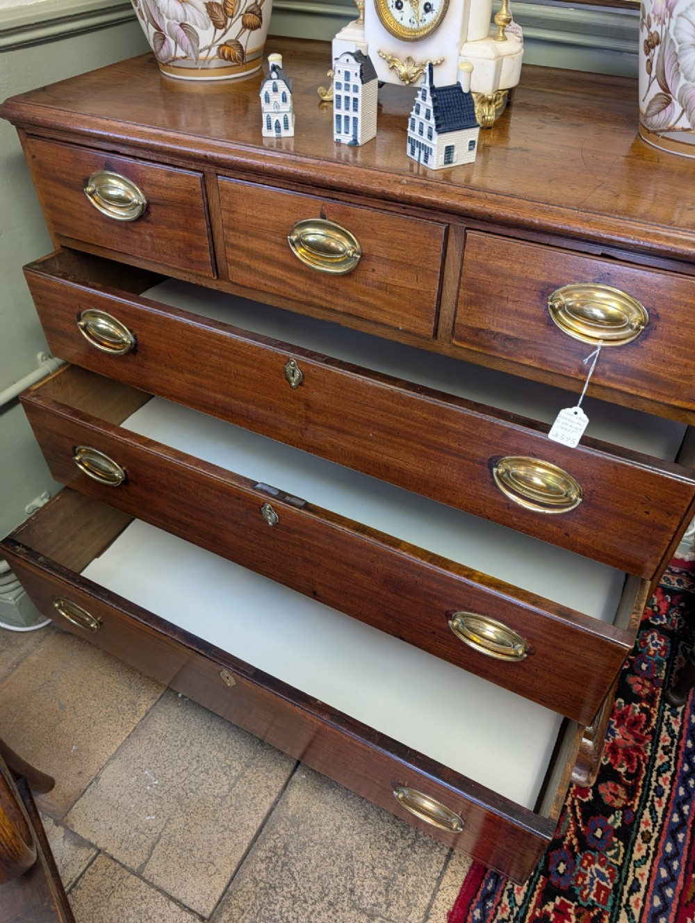A Georgian mahogany chest of drawers featuring three small upper drawers over three long graduated drawers with brass handles. View II