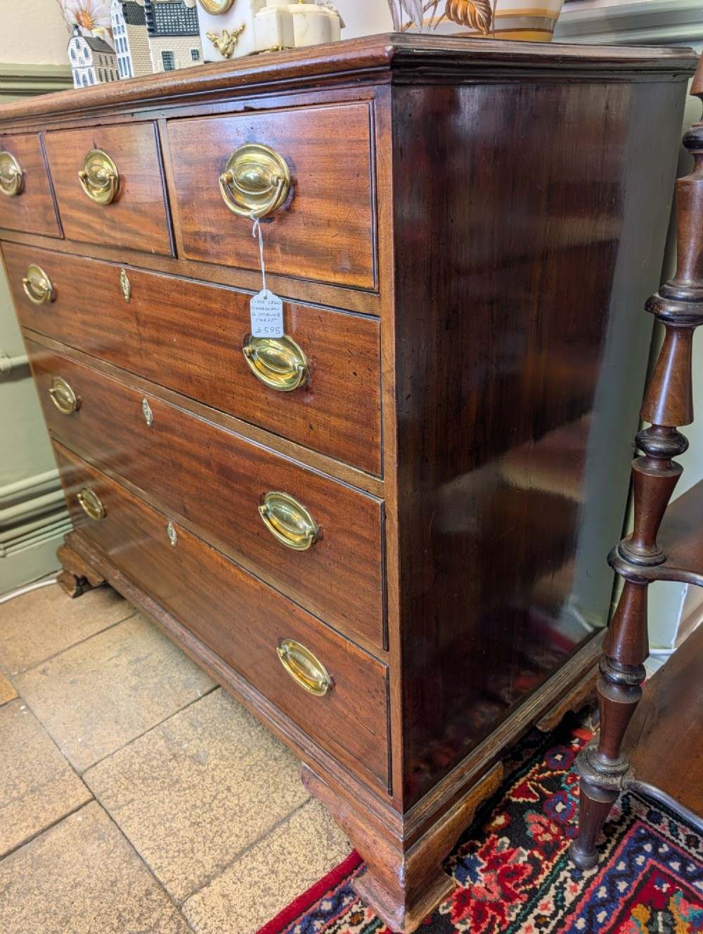 A Georgian mahogany chest of drawers featuring three small upper drawers over three long graduated drawers with brass handles. View V