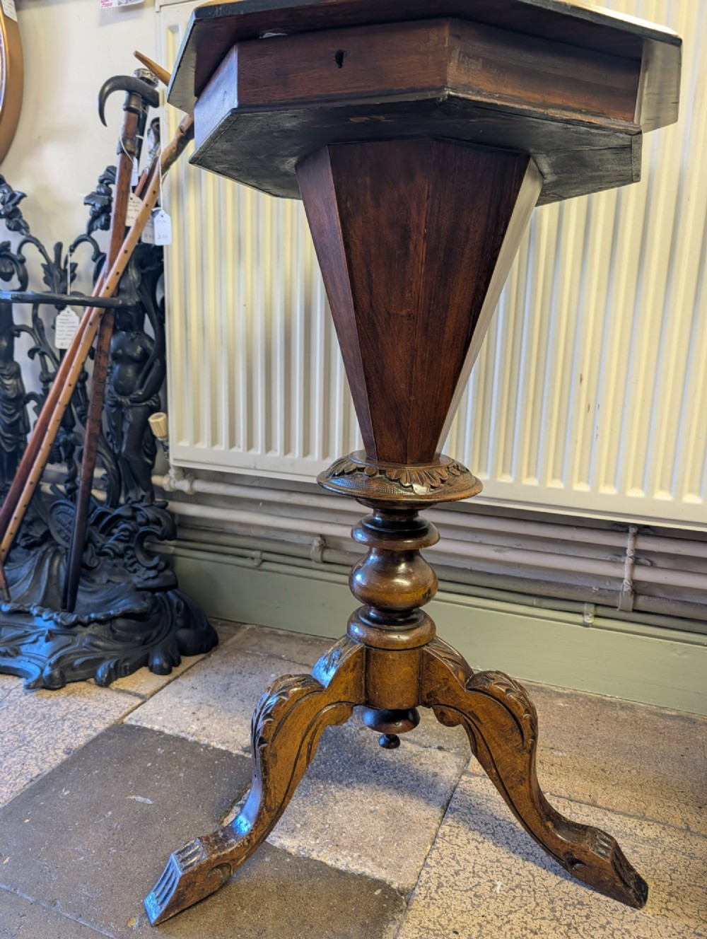A Victorian octagonal walnut games table featuring an inlaid chessboard lid above a tapering trumpet pedestal on carved tripod legs. View VII