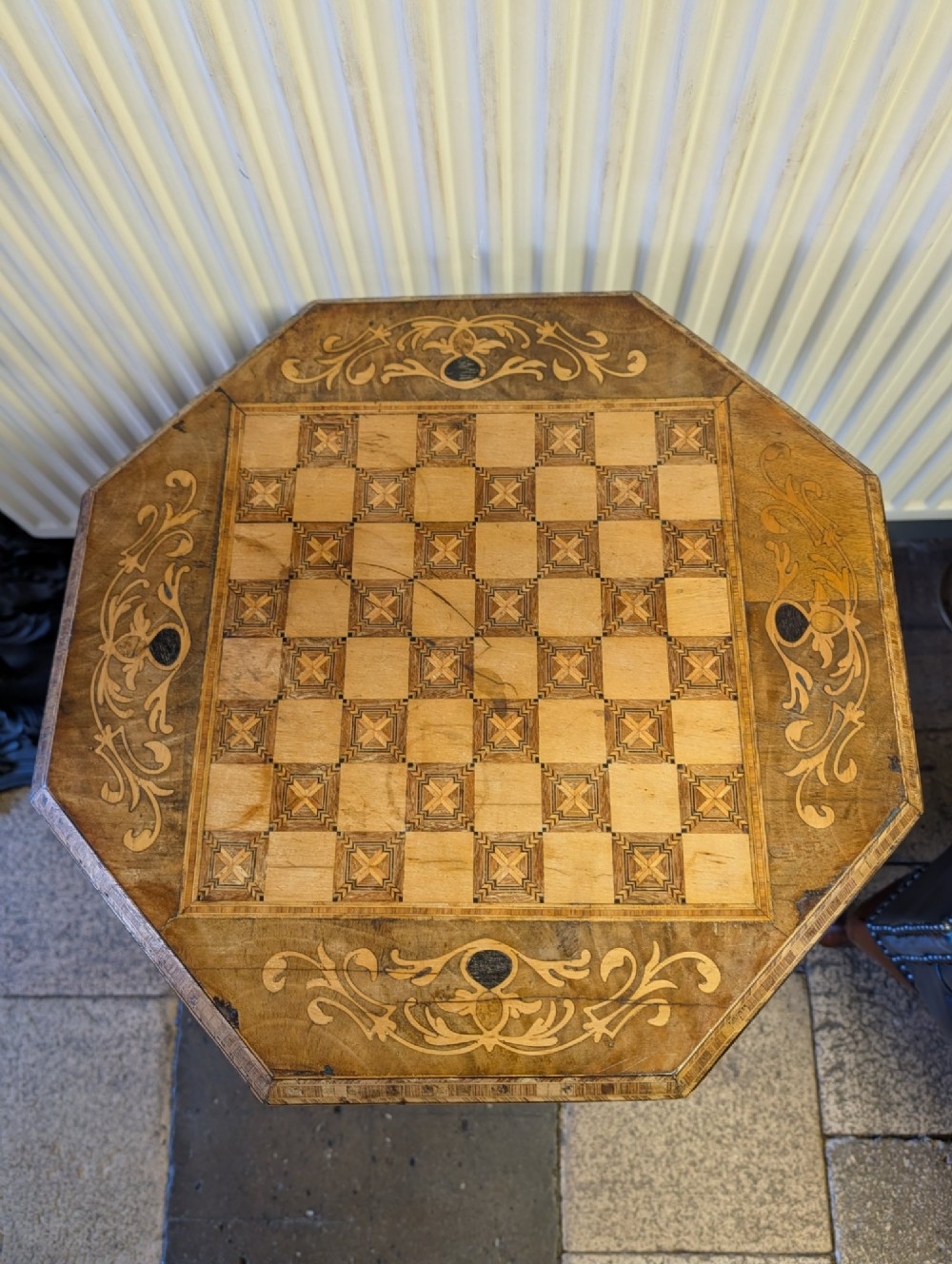 A Victorian octagonal walnut games table featuring an inlaid chessboard lid above a tapering trumpet pedestal on carved tripod legs. View VIII