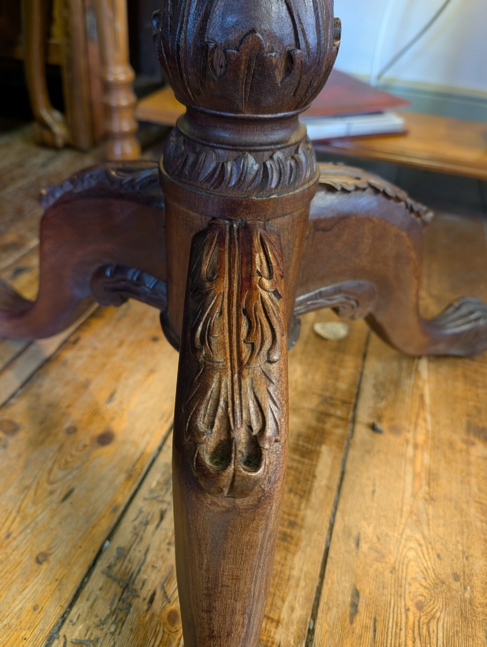 A top-down view of a 19th-century mahogany tilt-top table featuring a carved scalloped edge with shell motifs on a central turned pedestal base. View III