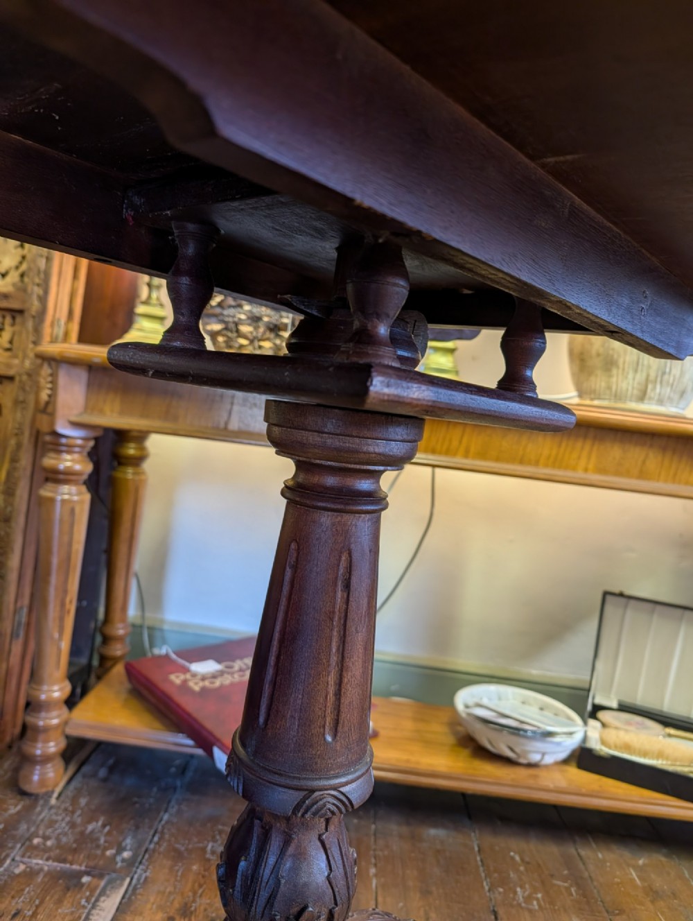 A top-down view of a 19th-century mahogany tilt-top table featuring a carved scalloped edge with shell motifs on a central turned pedestal base. View V
