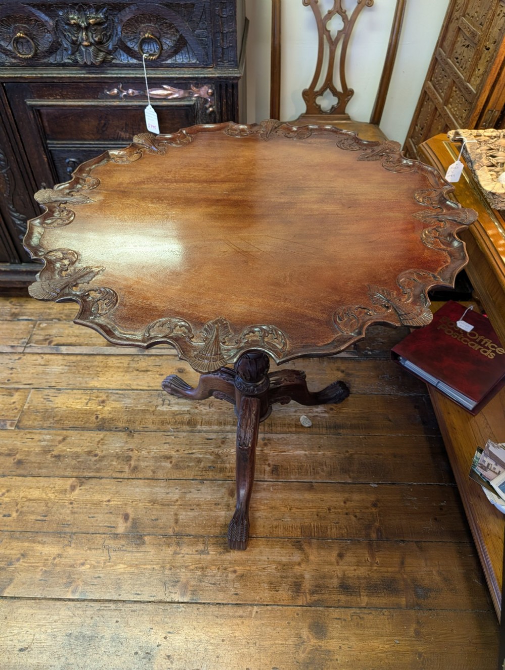 A top-down view of a 19th-century mahogany tilt-top table featuring a carved scalloped edge with shell motifs on a central turned pedestal base. View IX