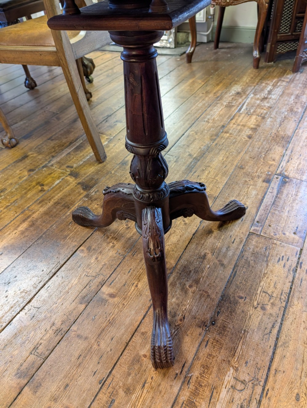 A top-down view of a 19th-century mahogany tilt-top table featuring a carved scalloped edge with shell motifs on a central turned pedestal base. View X