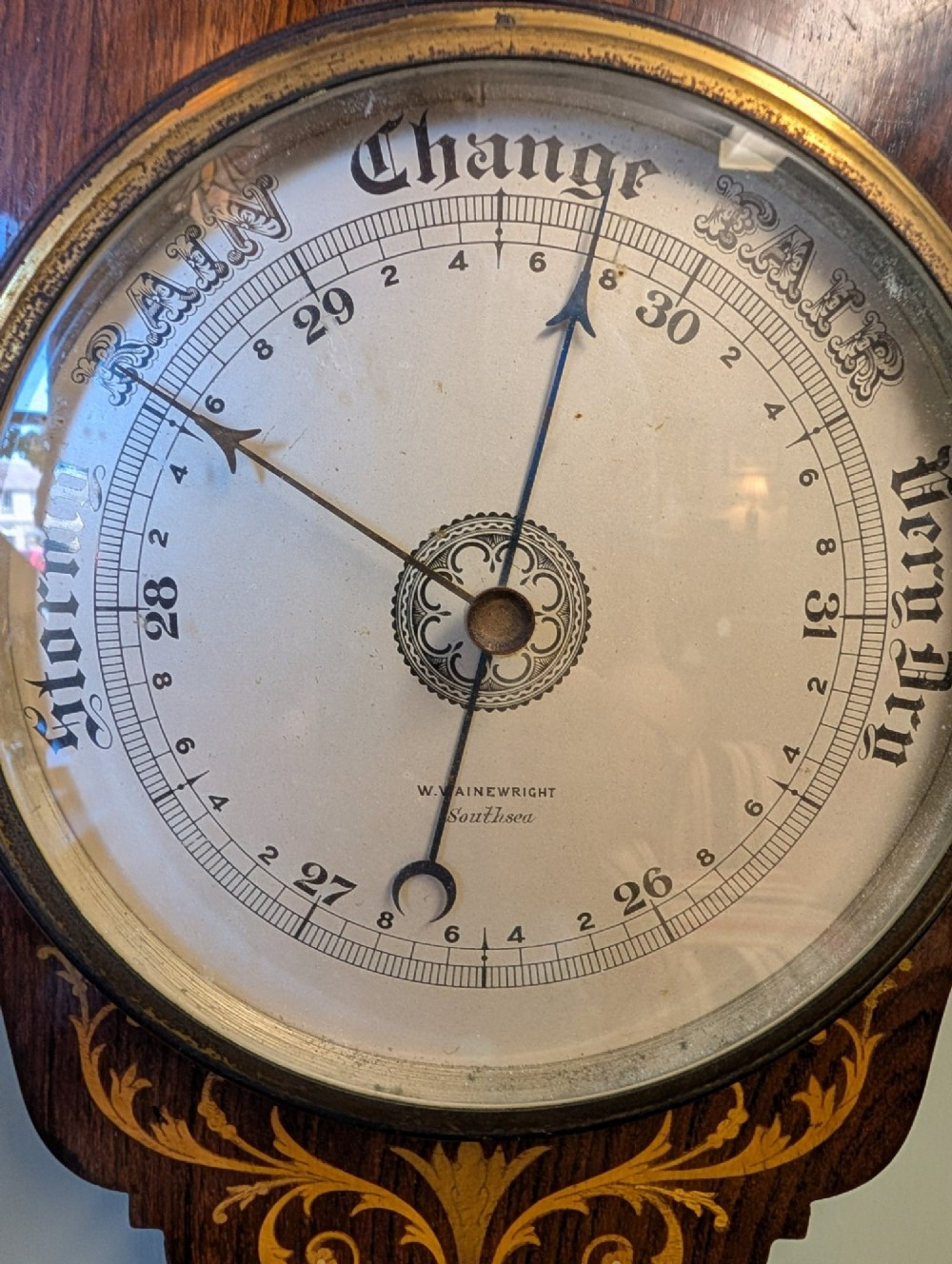 An Edwardian wall-mounted rosewood barometer featuring floral marquetry inlay, a top-mounted glass thermometer, and a circular brass-rimmed pressure dial. View VIII