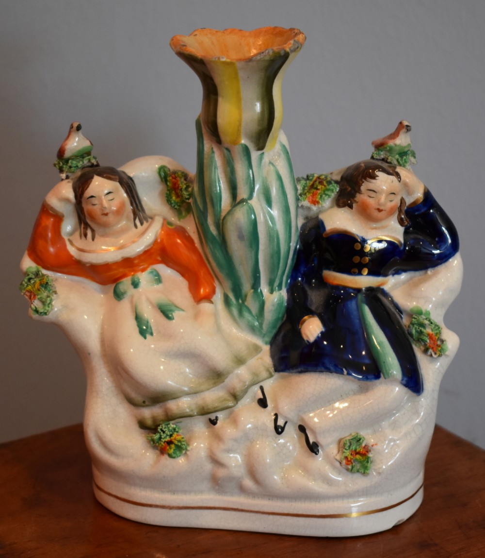 An antique Victorian Staffordshire earthenware spill vase depicting two reclining children under a central leaf-shaped vase spout with hand-painted polychrome enamels.