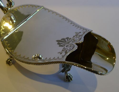 fig 1. A late Victorian silver-plated spoon warmer shaped like a sauce boat with an engraved hinged lid, high scroll handle, and four cast feet.