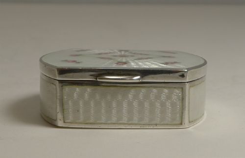 fig 1. An octagonal sterling silver pill box with a white guilloche enamel lid decorated with engine-turned sunburst patterns and hand-painted pink rose garlands.