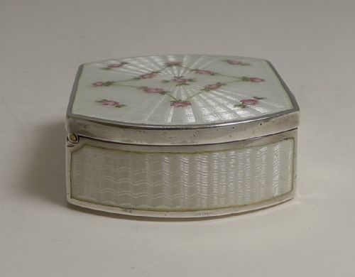 fig 2. An octagonal sterling silver pill box with a white guilloche enamel lid decorated with engine-turned sunburst patterns and hand-painted pink rose garlands.