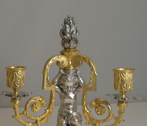 fig 1. A pair of French gilt and silvered bronze three-branch candelabra featuring kneeling cherubs and central flame finials.