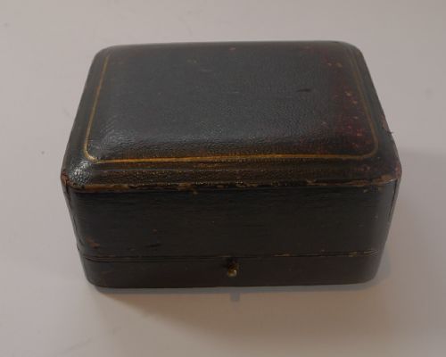 fig 1. A pair of embossed sterling silver pepper pots with fitted lids displayed inside a dark velvet-lined presentation case.