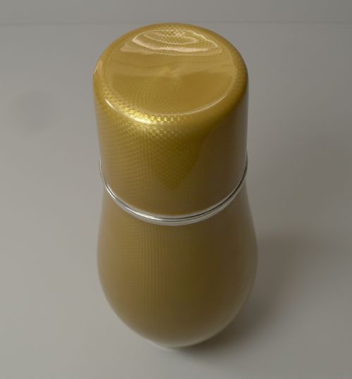 fig 1. A yellow guilloche enamel and sterling silver cocktail shaker with engine-turned geometric detailing.