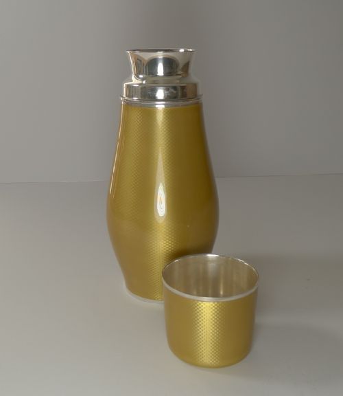 fig 2. A yellow guilloche enamel and sterling silver cocktail shaker with engine-turned geometric detailing.