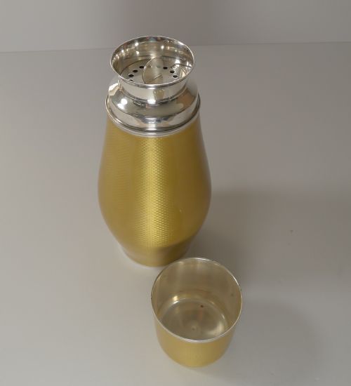 fig 3. A yellow guilloche enamel and sterling silver cocktail shaker with engine-turned geometric detailing.