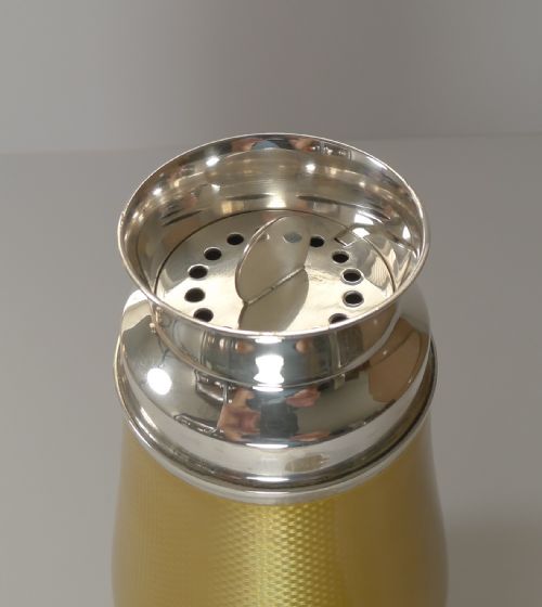 fig 4. A yellow guilloche enamel and sterling silver cocktail shaker with engine-turned geometric detailing.