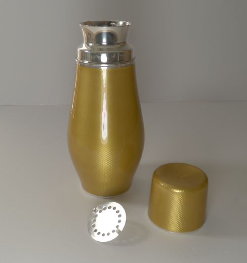 fig 5. A yellow guilloche enamel and sterling silver cocktail shaker with engine-turned geometric detailing.