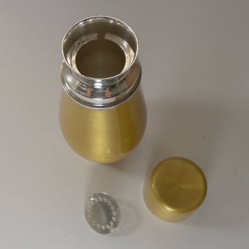 fig 6. A yellow guilloche enamel and sterling silver cocktail shaker with engine-turned geometric detailing.