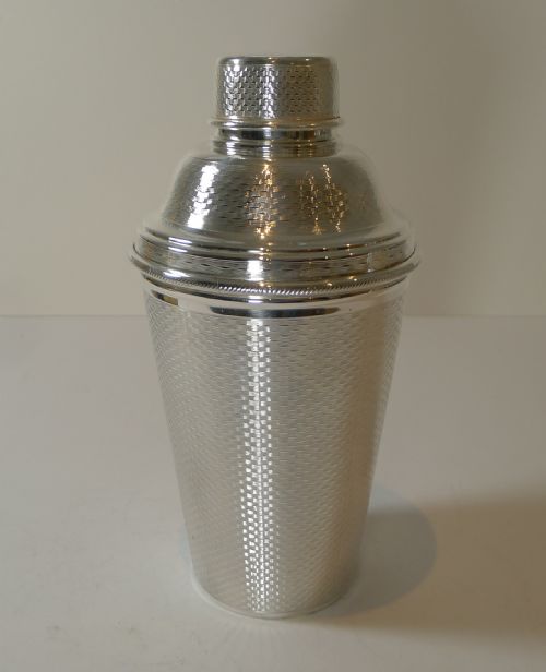 fig 1. A large three-piece silver-plated Art Deco cocktail shaker featuring an engine-turned geometric pattern across the exterior.