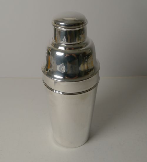 fig 2. An Art Deco silver-plated cocktail shaker presented disassembled, showing the main body, cap, and strainer lid with an integrated internal ice breaker mechanism.
