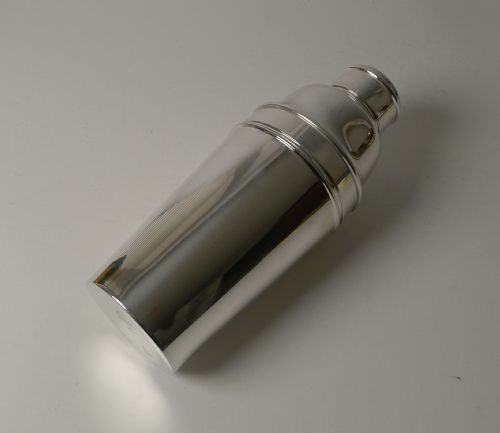fig 3. An Art Deco silver-plated cocktail shaker presented disassembled, showing the main body, cap, and strainer lid with an integrated internal ice breaker mechanism.