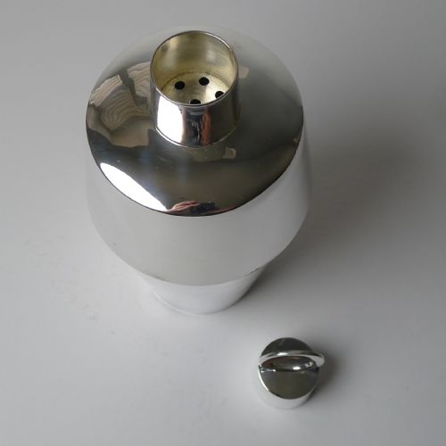 fig 1. A polished silver-plated Art Deco cocktail shaker featuring a tapered lower body and a cylindrical cap topped with a circular ring finial.