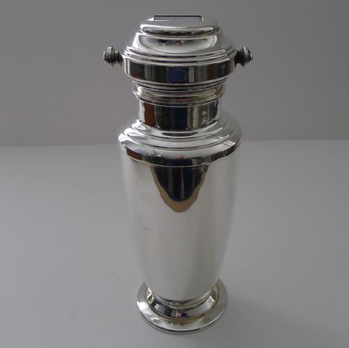 fig 1. A silver-plated Art Deco cocktail shaker featuring a rotating top cap with rectangular windows displaying drink recipes.