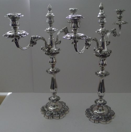 fig 2. A pair of ornate silver-plated multi-branch candelabra featuring scrolled foliage arms and decorative stepped bases.