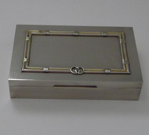 fig 1. A rectangular silver table box featuring a geometric wire-wrapped border detail and double G emblem on the hinged lid.