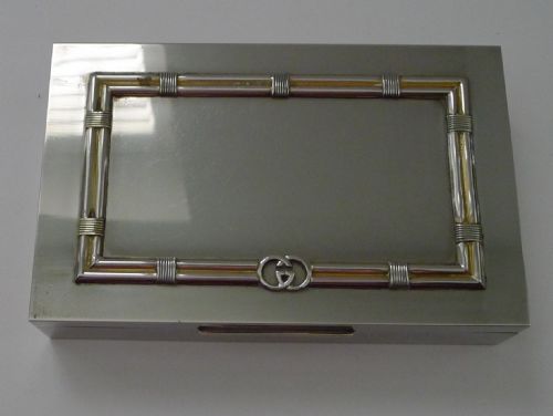 fig 2. A rectangular silver table box featuring a geometric wire-wrapped border detail and double G emblem on the hinged lid.