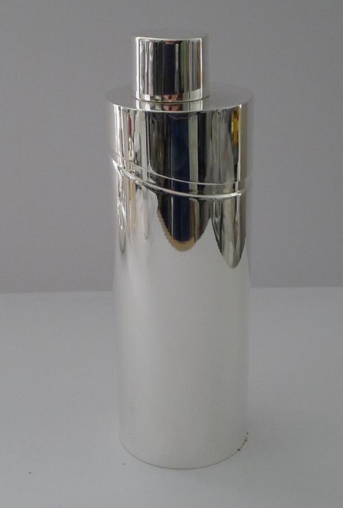 fig 1. A sleek, highly polished cylindrical silver-plated cocktail shaker with an angled upper seam and fitted cylindrical cap.