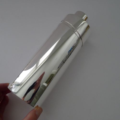 fig 4. A sleek, highly polished cylindrical silver-plated cocktail shaker with an angled upper seam and fitted cylindrical cap.