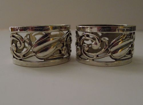 fig 1. A pair of pierced sterling silver napkin rings with foliage motifs resting inside a red Cartier presentation box.