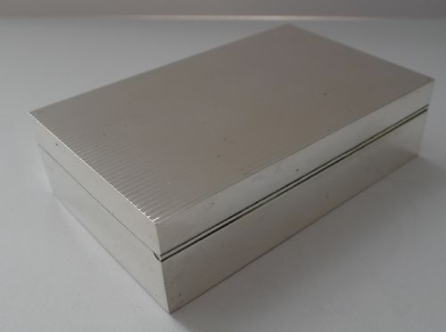fig 2. A rectangular sterling silver cigarette box with an engine-turned reeded pattern on the lid and a plain central rectangular cartouche.