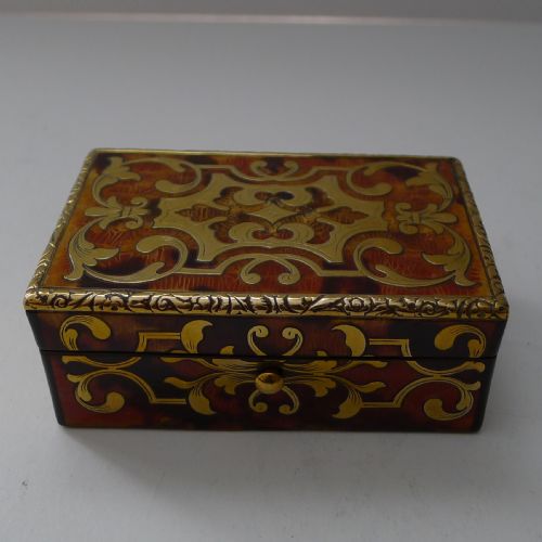 fig 1. A small rectangular 19th-century French Boulle trinket box featuring intricate brass foliate inlay over a tortoiseshell pattern with chased metal edging.