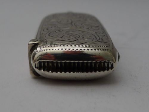 fig 2. An open Edwardian sterling silver combined sovereign holder and vesta case with hand-engraved foliate patterns and a suspension ring.
