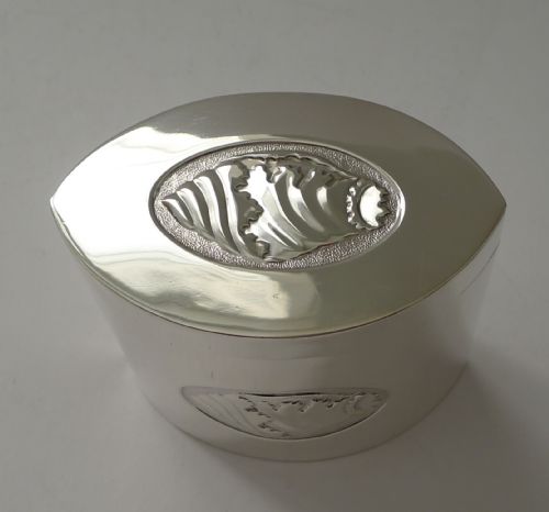 fig 1. An oval Edwardian sterling silver tea caddy featuring relief seashell panels on the lid and front surface.