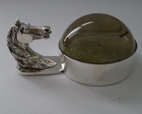 fig 1. A silver-plated horse head handle joined to a clear glass dome magnifying paperweight.
