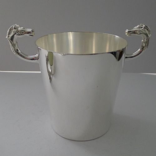 fig 1. A polished silver-plated ice bucket featuring sculpted horse heads serving as side handles on a smooth cylindrical body.