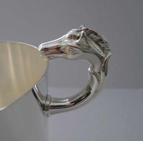 fig 2. A polished silver-plated ice bucket featuring sculpted horse heads serving as side handles on a smooth cylindrical body.
