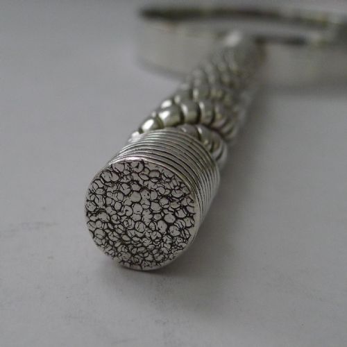fig 2. A vintage silver-plated magnifying glass featuring a circular lens and a textured twisted rope pattern handle.
