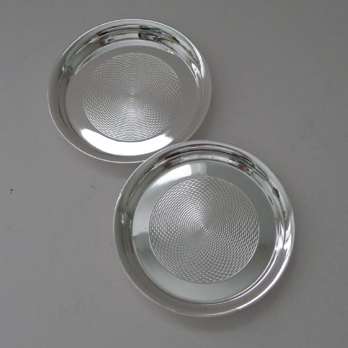 fig 1. A pair of circular silver-plated coasters featuring raised rims and engine-turned concentric circle patterns.