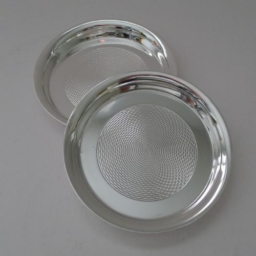 fig 2. A pair of circular silver-plated coasters featuring raised rims and engine-turned concentric circle patterns.