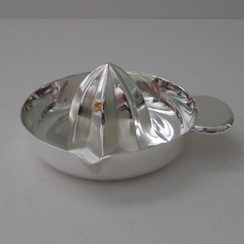 fig 1. A circular silver-plated Art Deco lemon squeezer featuring a central ridged reaming cone, a side handle, and an integrated spout.