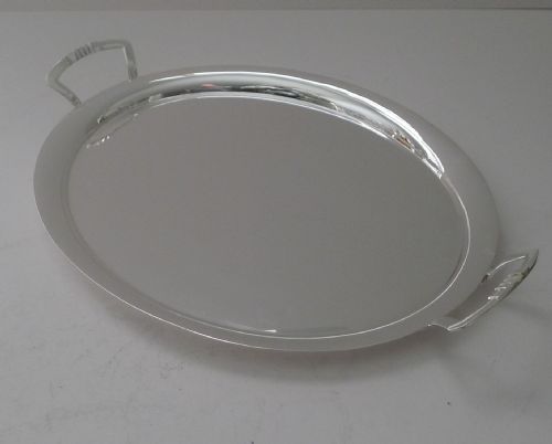 fig 1. An oval silver-plated cocktail tray featuring a flat polished surface, raised rim, and two geometric angular side handles.